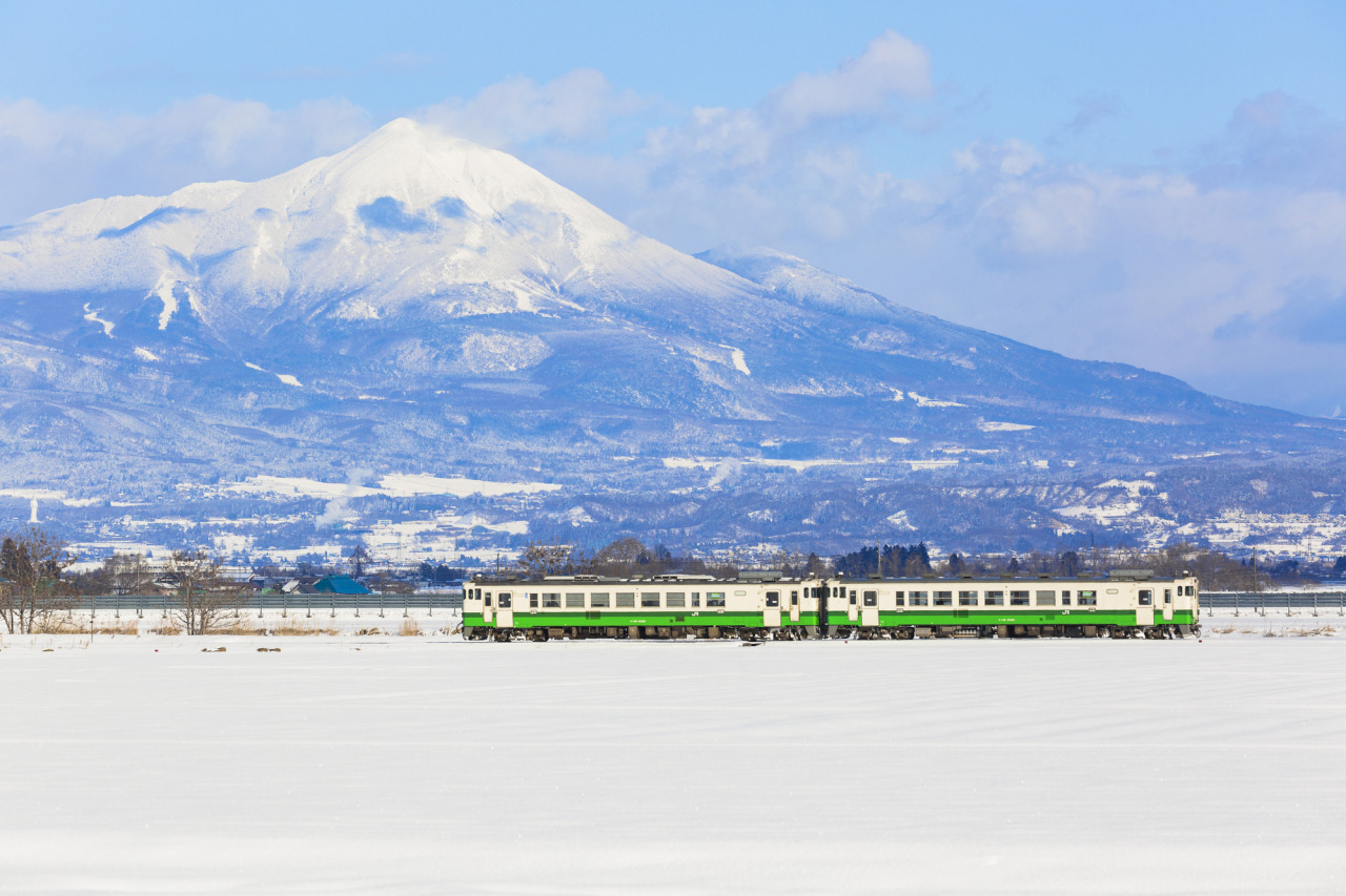 磐梯山を背景に雪原を走る只見線